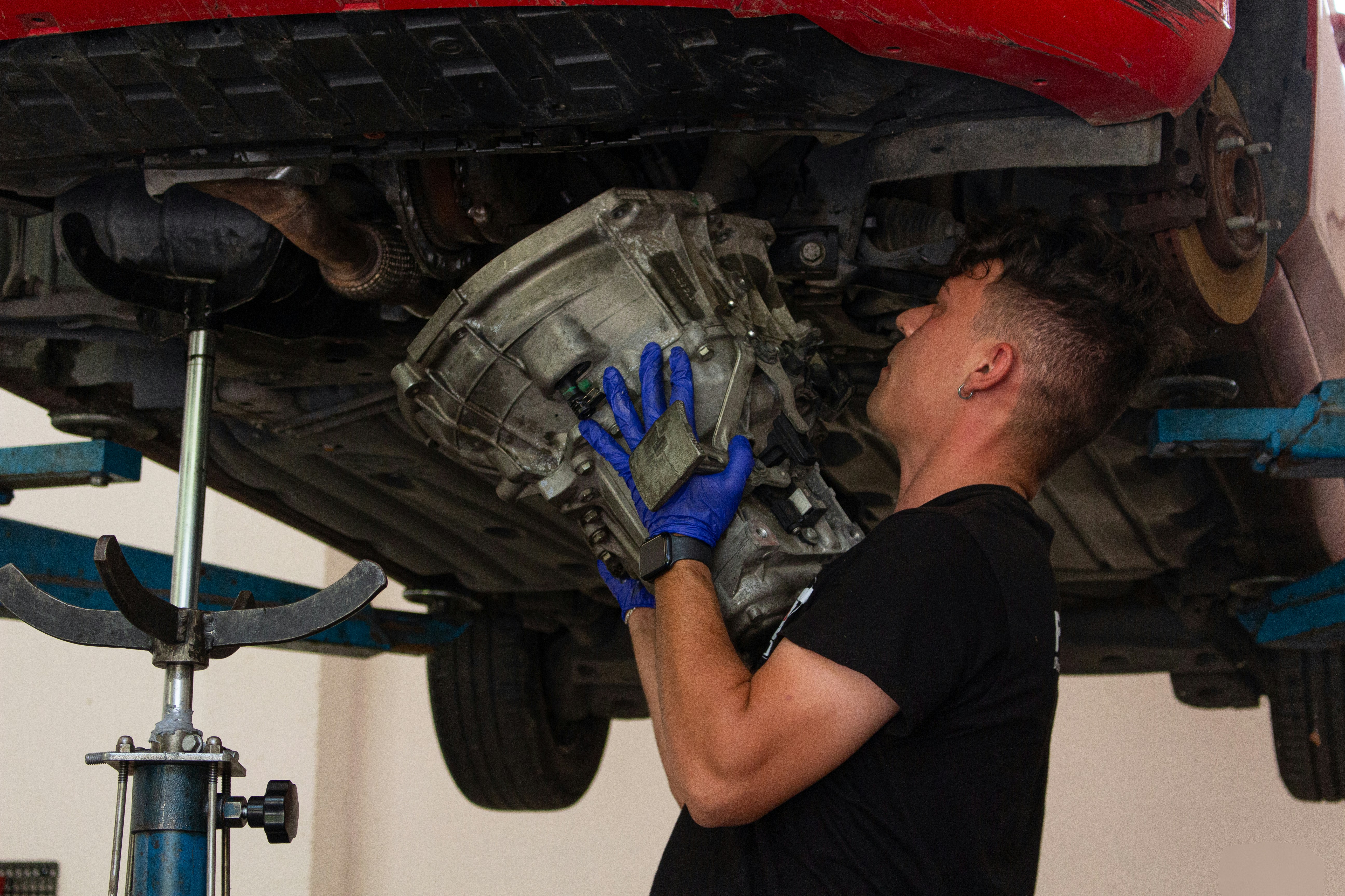 Mechanic installing transmission under vehicle